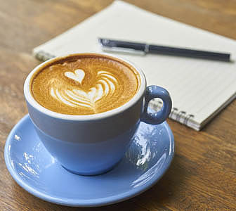 Ein Notizblock und eine Tasse Cappuccino